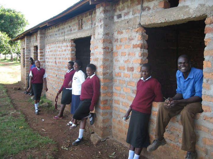 Pupils and cook John in front of an unfinished house.